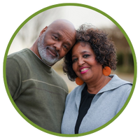 Older, in love, lovely Black couple standing side-by-side with heads tilted toward and touching each other.